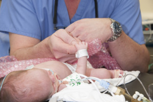 surgeon holding premature baby's hand